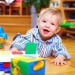 cute baby boy playing with toys in living room